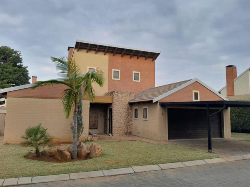 Front elevation of a two-story townhouse featuring a combination of brick and stone cladding, a garage, and a paved driveway.