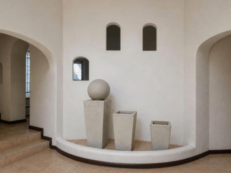 A spacious entry hall featuring elegant arched doorways, tiled flooring, and a decorative curved wall niche with architectural recessed openings.