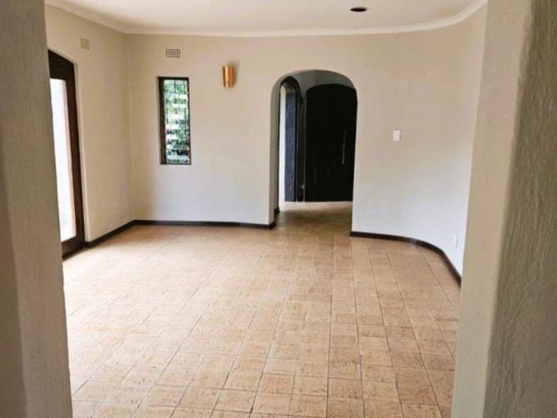 An empty, light-filled living area featuring classic arched doorways, neutral walls, and durable tiled flooring, offering a versatile space for interior design.
