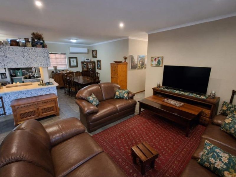 Spacious open-plan living and dining area featuring tiled flooring, recessed lighting, and a functional kitchen breakfast bar with decorative tiling.