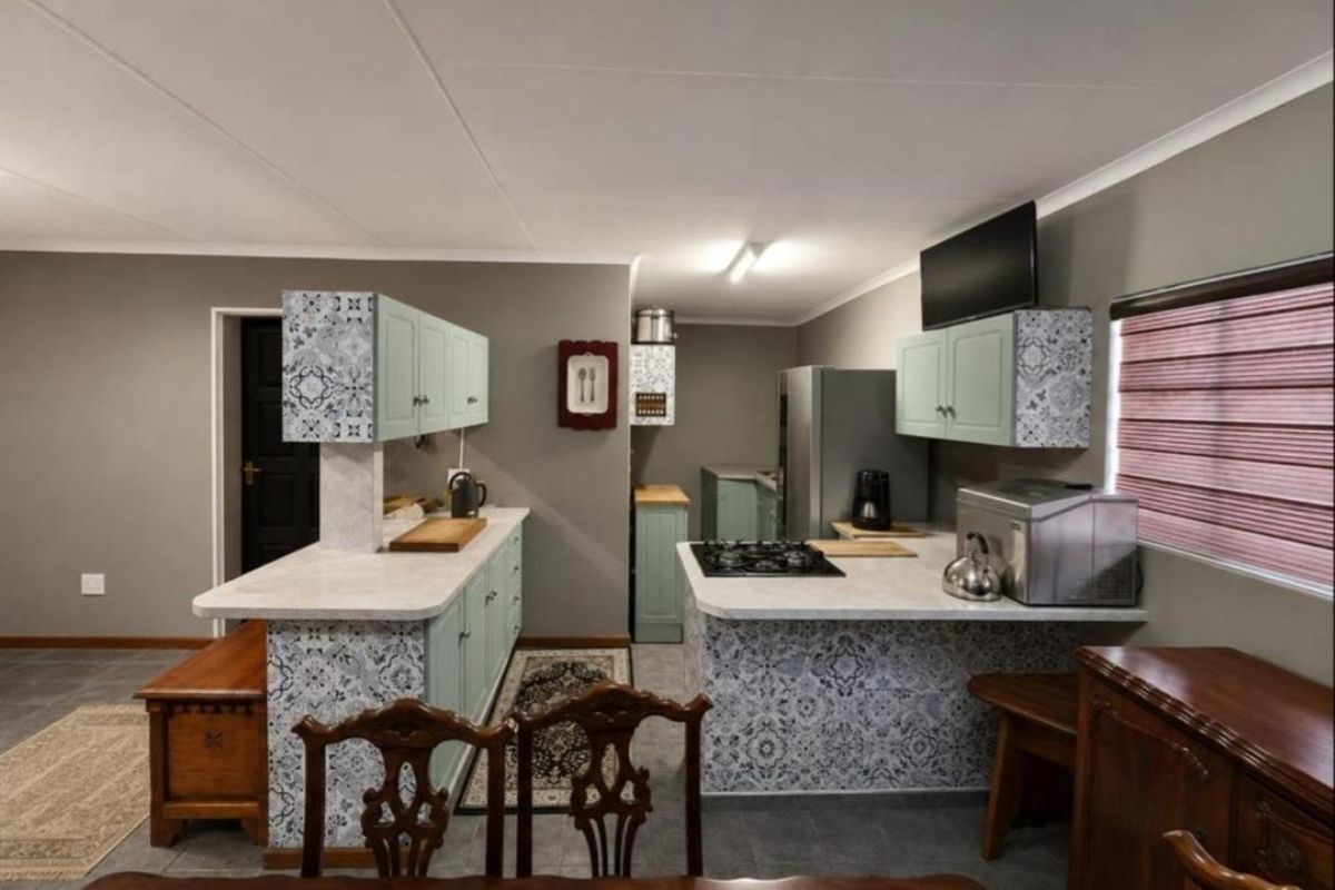 A functional kitchen featuring patterned tiled cabinetry, laminate countertops, a gas hob, and tiled flooring, offering a practical layout for cooking and preparation.