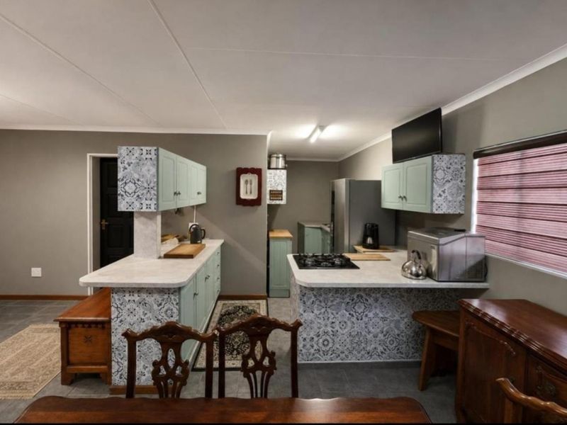 A functional kitchen featuring patterned tiled cabinetry, laminate countertops, a gas hob, and tiled flooring, offering a practical layout for cooking and preparation.