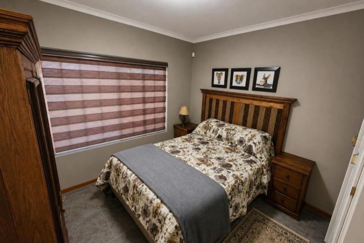 A well-maintained bedroom featuring tiled flooring, neutral wall tones, and modern roller blinds, providing a comfortable and functional living space.