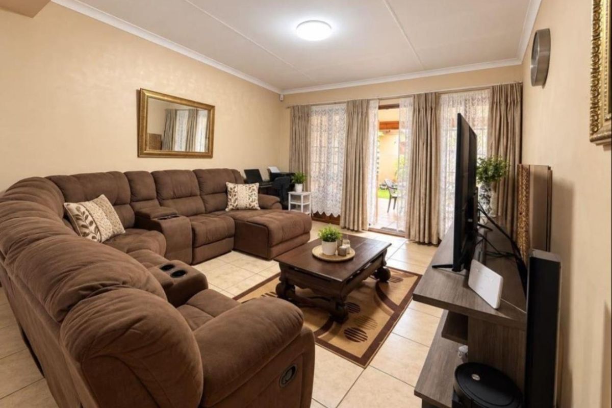 A comfortable living room featuring tiled flooring, coved ceilings, and sliding glass doors that provide direct access to the outdoor patio area.
