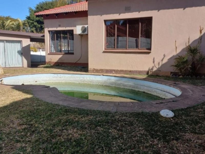 Rear exterior view featuring a swimming pool with brick coping, adjacent to the main house structure with a tiled roof and exterior air conditioning unit.