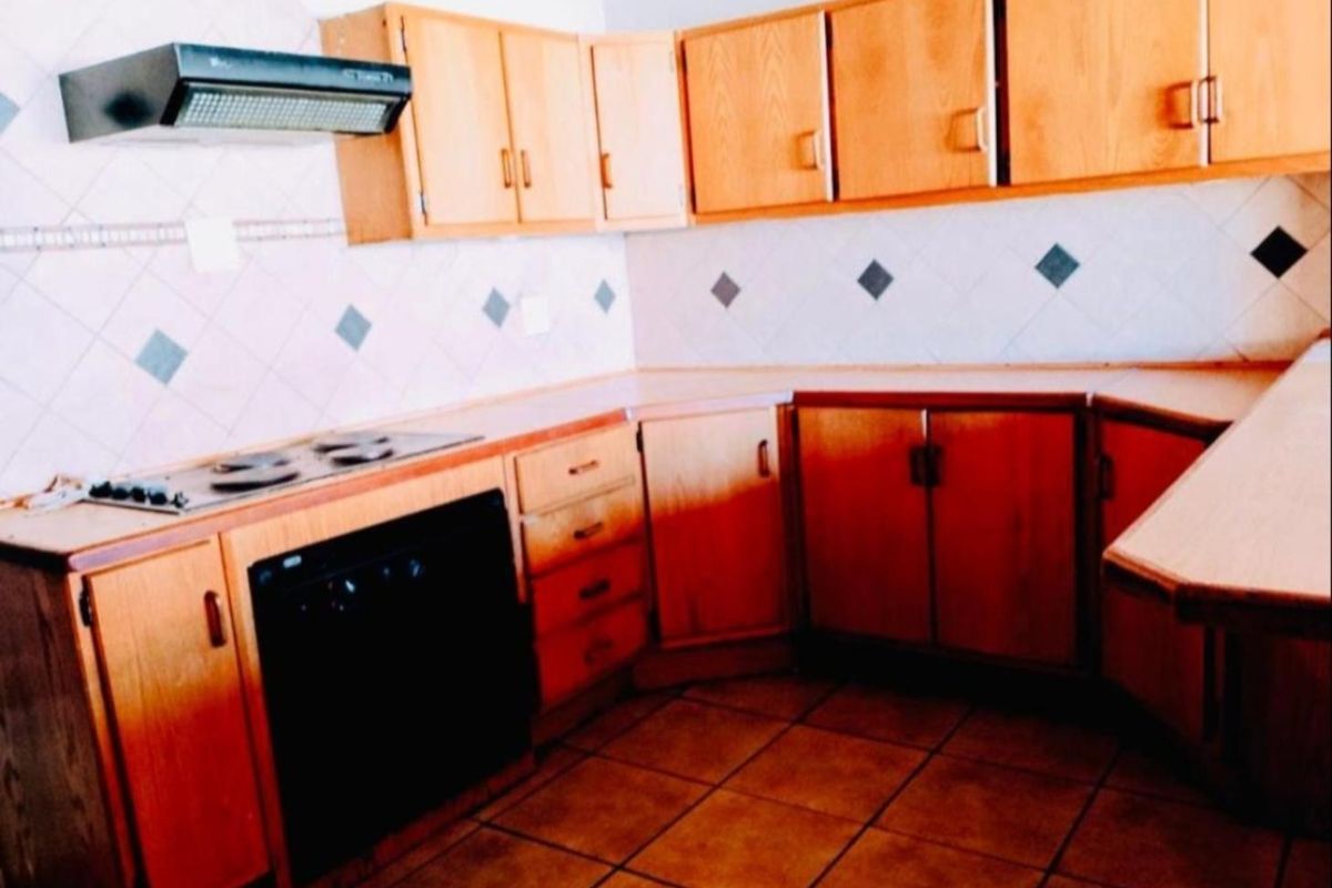A dated kitchen featuring wooden cabinetry, laminate countertops, built-in oven, and tiled finishes, offering potential for a modern renovation.