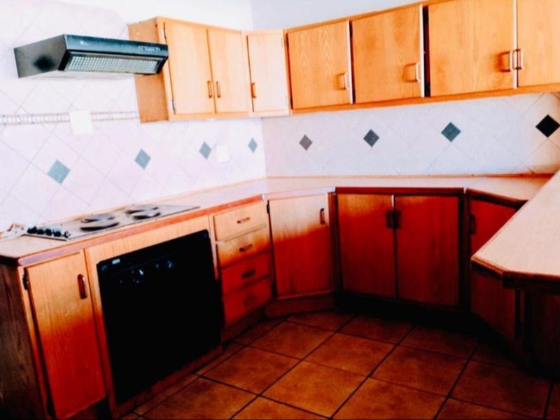 A dated kitchen featuring wooden cabinetry, laminate countertops, built-in oven, and tiled finishes, offering potential for a modern renovation.