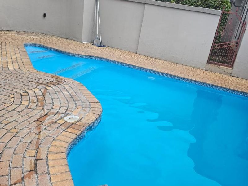 A private swimming pool area featuring brick paving surround and a secure boundary wall, providing a clean and functional outdoor space.
