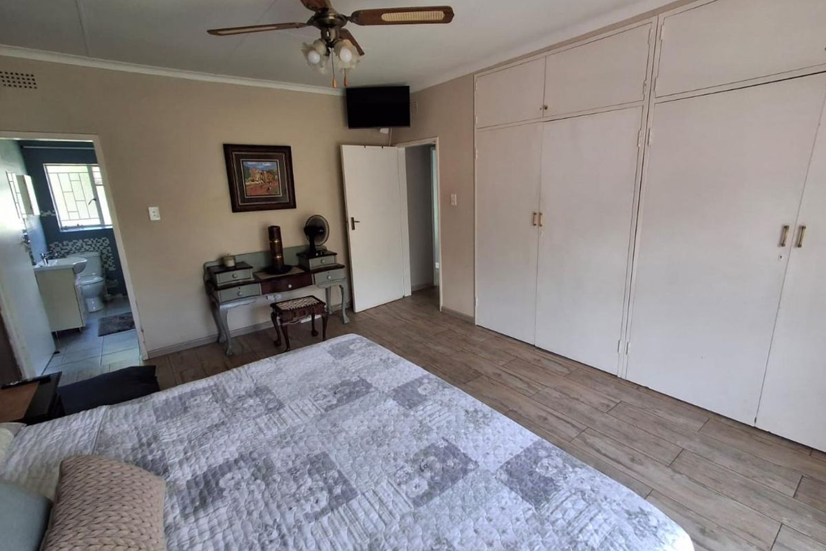 Spacious bedroom featuring built-in cupboards, tiled flooring, and an en-suite bathroom access.