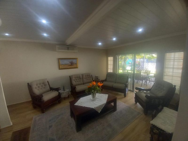 A comfortable living room featuring laminate flooring, recessed downlighting, and sliding glass doors that provide access to the outdoor patio area.
