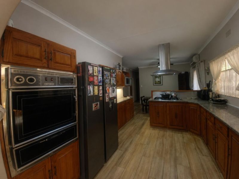 Spacious kitchen featuring wooden cabinetry, granite countertops, built-in oven, and a modern extractor fan, with durable laminate flooring throughout.