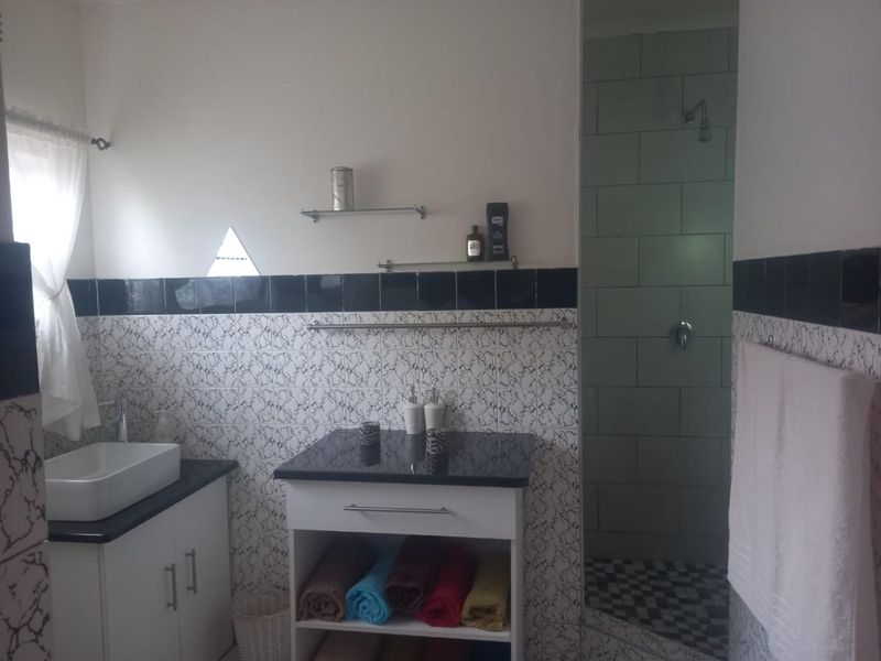 A functional bathroom featuring a vessel sink with a granite vanity, a separate shower enclosure, and decorative tiled wall accents.