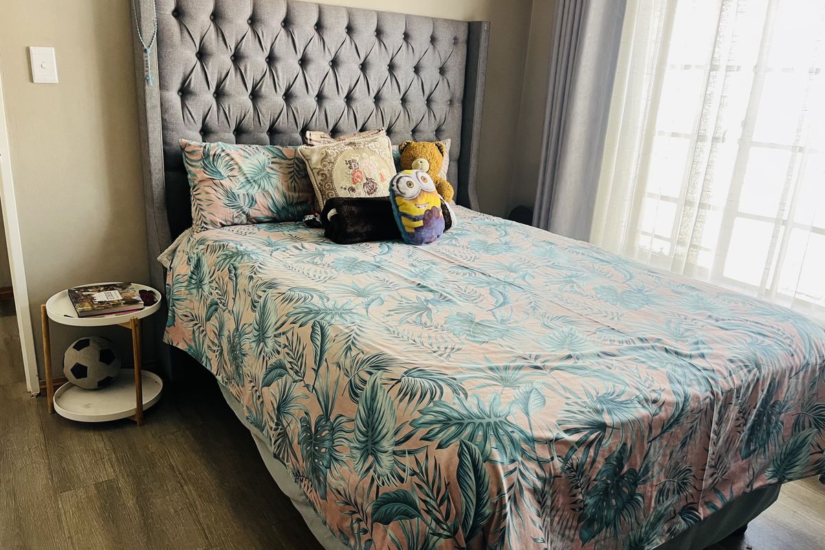 A well-maintained bedroom featuring laminate flooring and neutral wall finishes, providing a comfortable and functional living space.