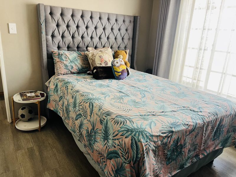 A well-maintained bedroom featuring laminate flooring and neutral wall finishes, providing a comfortable and functional living space.