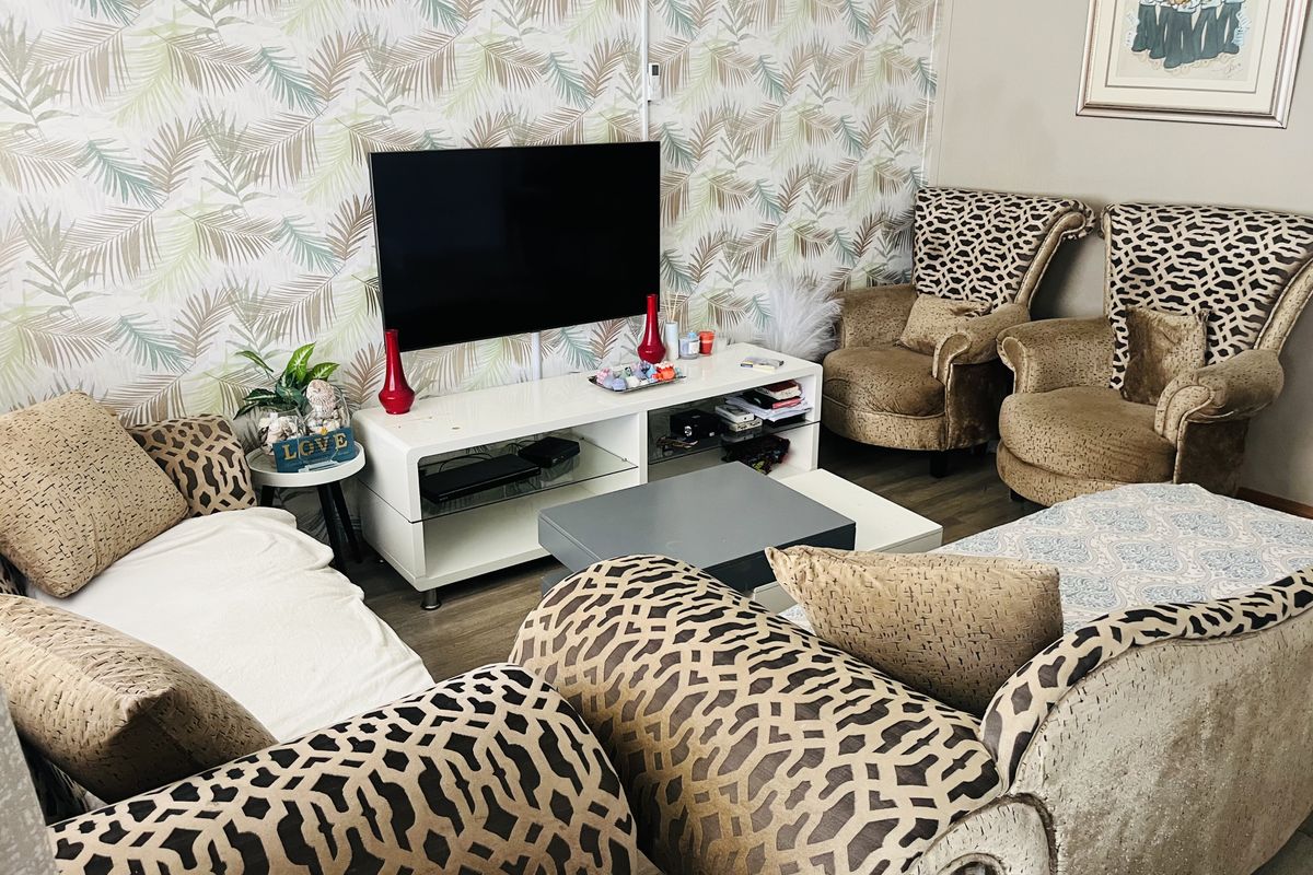 A living room featuring patterned wallpaper and laminate flooring, providing a functional space for relaxation and entertainment.