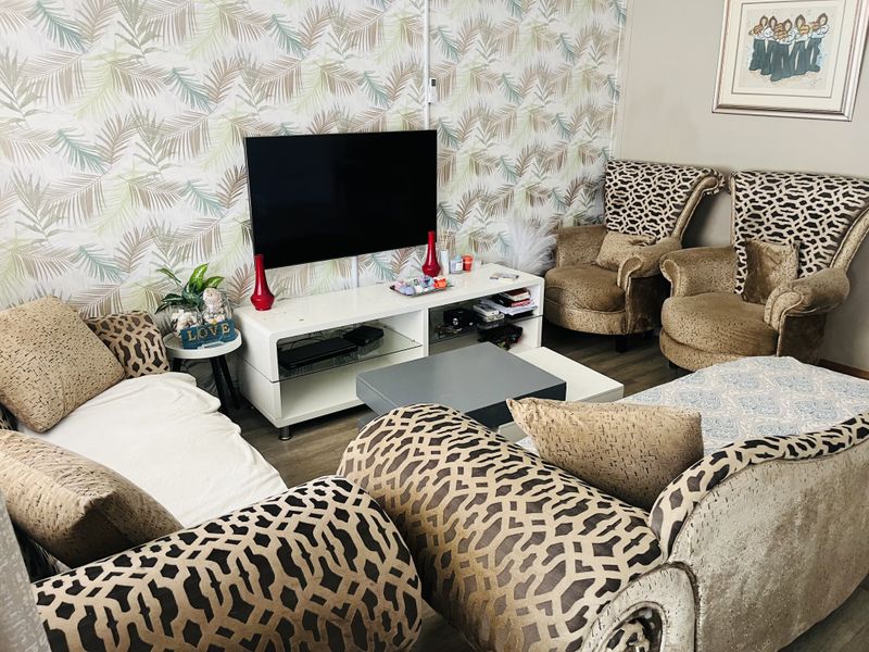 A living room featuring patterned wallpaper and laminate flooring, providing a functional space for relaxation and entertainment.