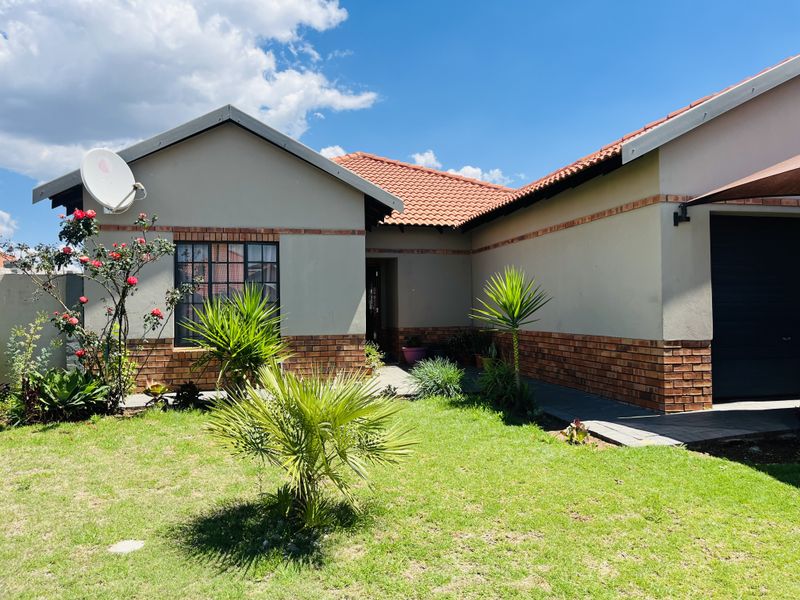 Front view of a well-maintained single-story house featuring a brick and plaster facade, tiled roof, and a neat front garden with a paved walkway.