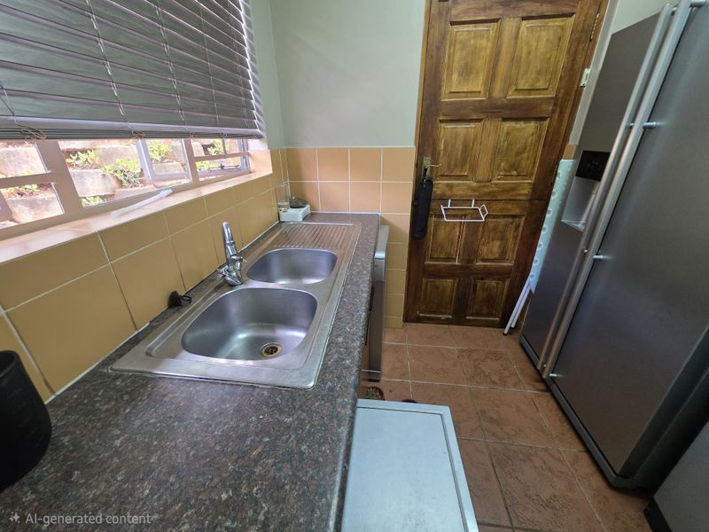 Functional scullery area featuring a double bowl stainless steel sink, laminate countertops, and ceramic tiling throughout.