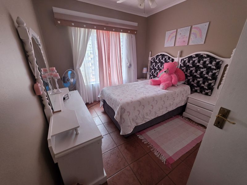 A cozy bedroom featuring tiled flooring, a ceiling fan, and a curtain pelmet, offering a comfortable and functional living space.