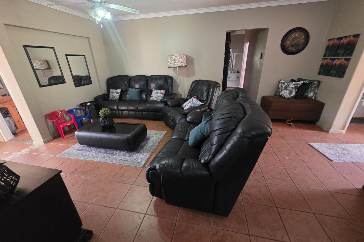 Spacious living room featuring tiled flooring, coved cornicing, and a ceiling fan, providing a comfortable and functional area for relaxation.