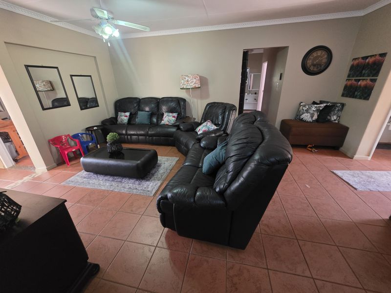 Spacious living room featuring tiled flooring, coved cornicing, and a ceiling fan, providing a comfortable and functional area for relaxation.