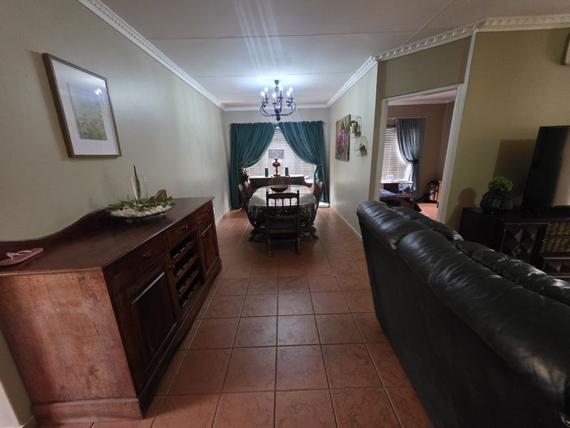 Open plan living and dining area featuring ceramic tile flooring, decorative crown molding, and a central chandelier, providing a functional and connected living space.