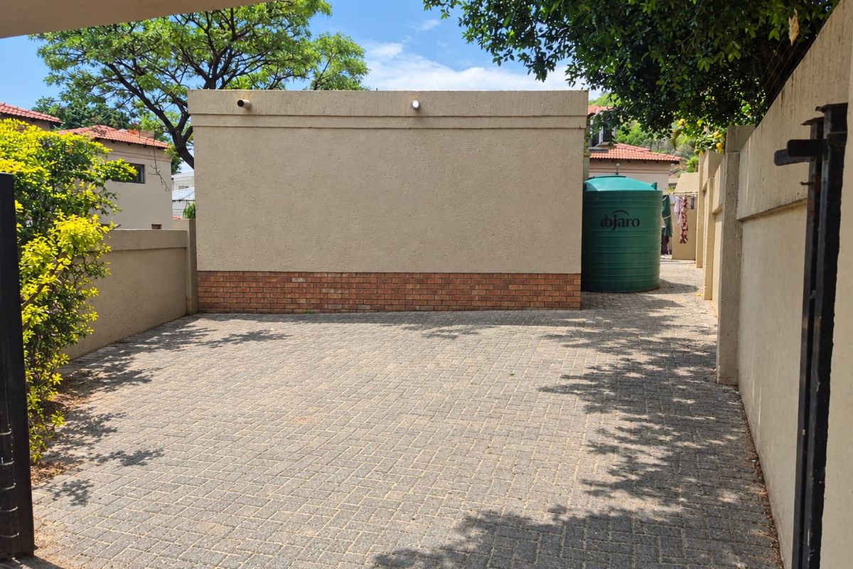 A paved rear courtyard area featuring a boundary wall and a large water storage tank, providing a functional outdoor utility space.