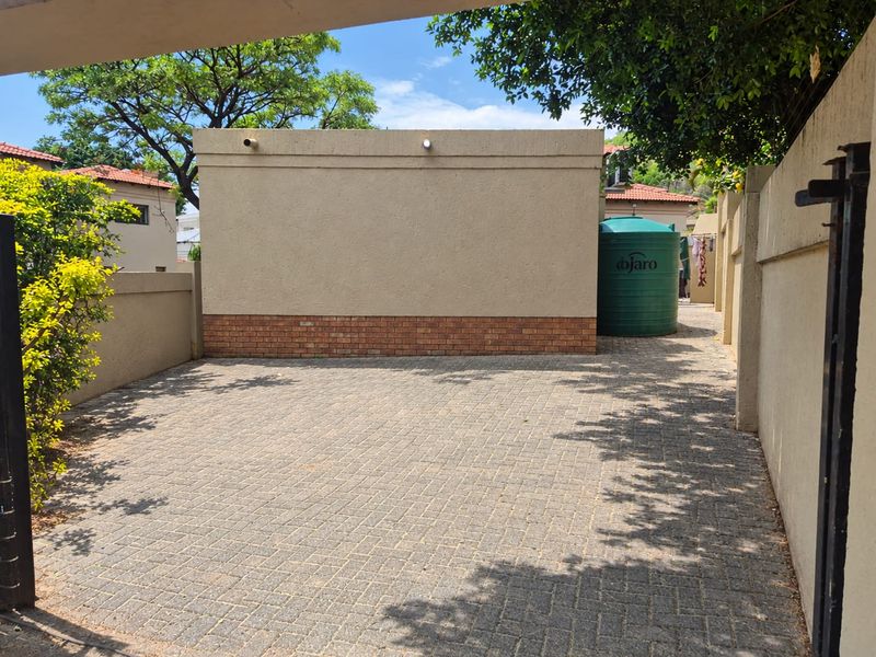 A paved rear courtyard area featuring a boundary wall and a large water storage tank, providing a functional outdoor utility space.