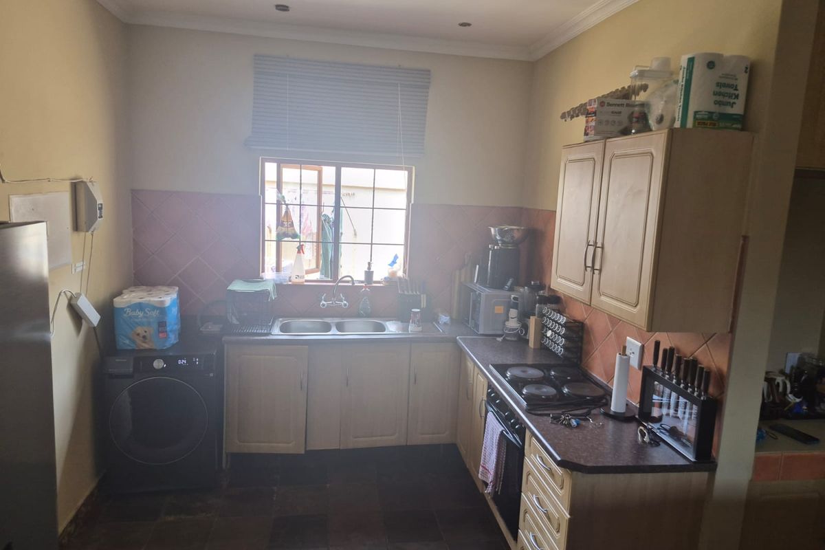 Functional kitchen featuring built-in cabinetry, double sink, electric hob, and oven with tiled backsplash and flooring.