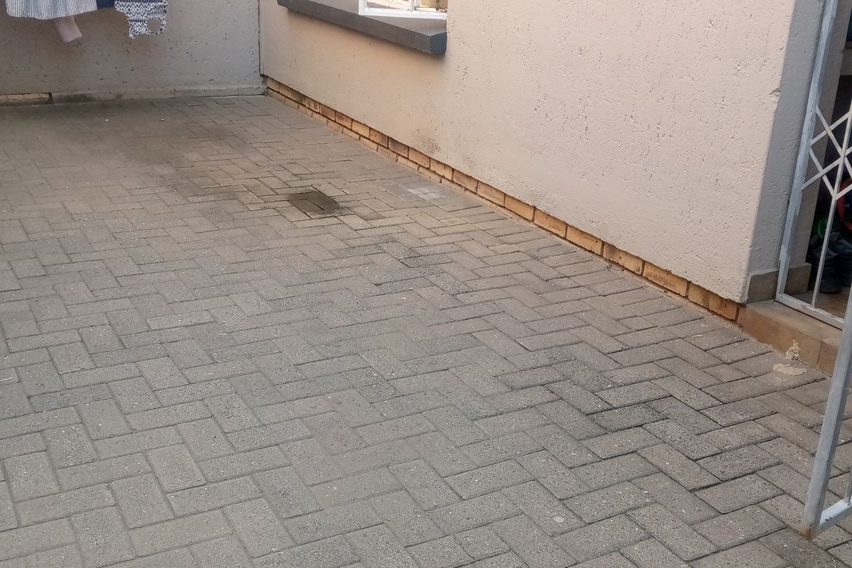 A paved rear courtyard area featuring a security gate and drainage point, providing a functional outdoor space for the flat.