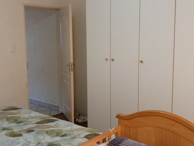 A bedroom featuring white built-in cupboards and an internal door leading to an adjacent space.