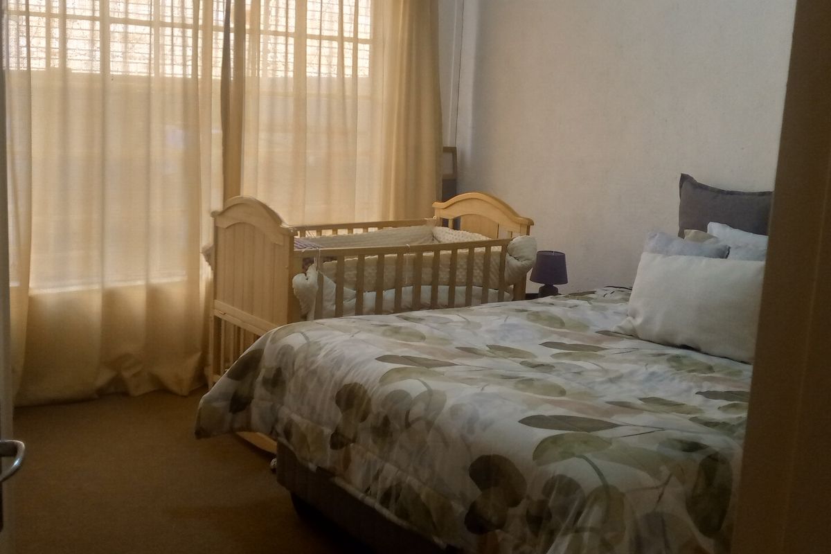 A bedroom featuring carpeted flooring and large windows with curtains, providing a functional space for rest.