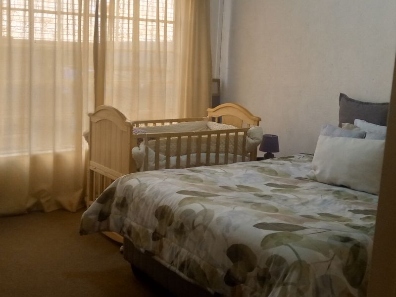 A bedroom featuring carpeted flooring and large windows with curtains, providing a functional space for rest.