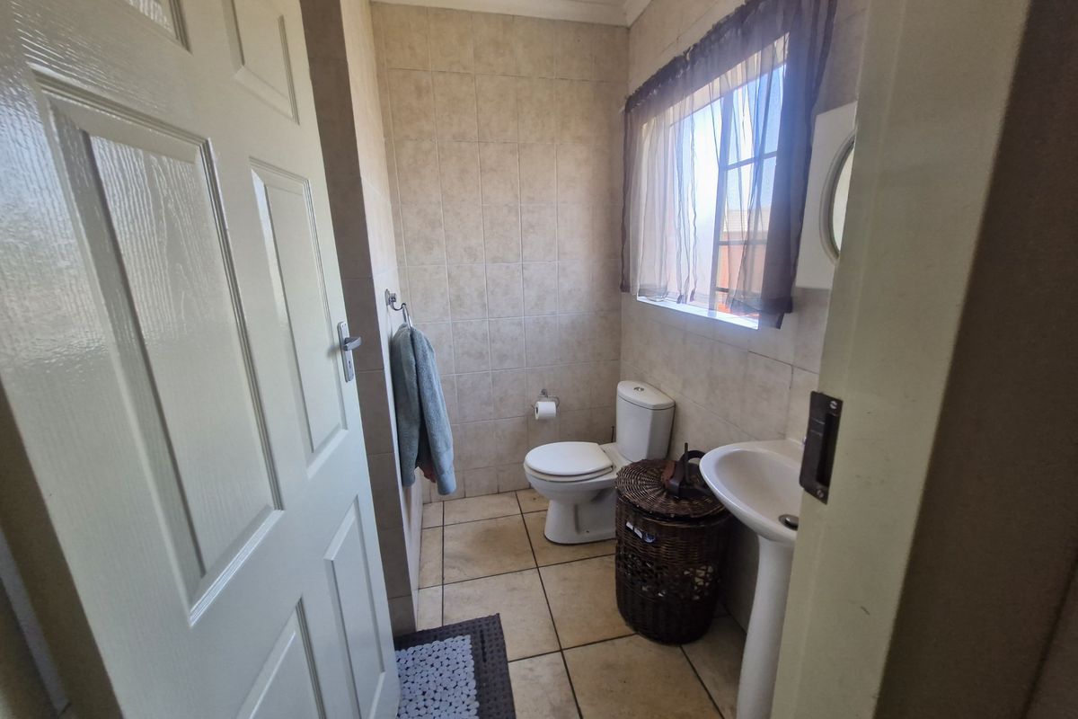 A functional guest bathroom featuring tiled walls and flooring, a pedestal basin, and a standard toilet.