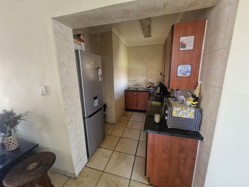 A functional scullery area featuring tiled flooring, wall tiling, laminate cabinetry, granite countertops, and a stainless steel sink.
