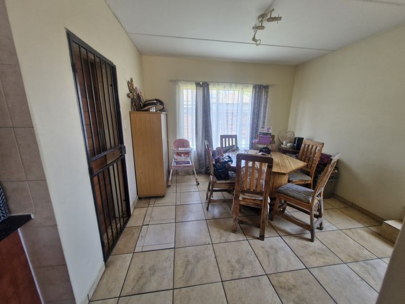 Dining area featuring tiled flooring and a security gate, providing a functional space with potential for cosmetic updates.