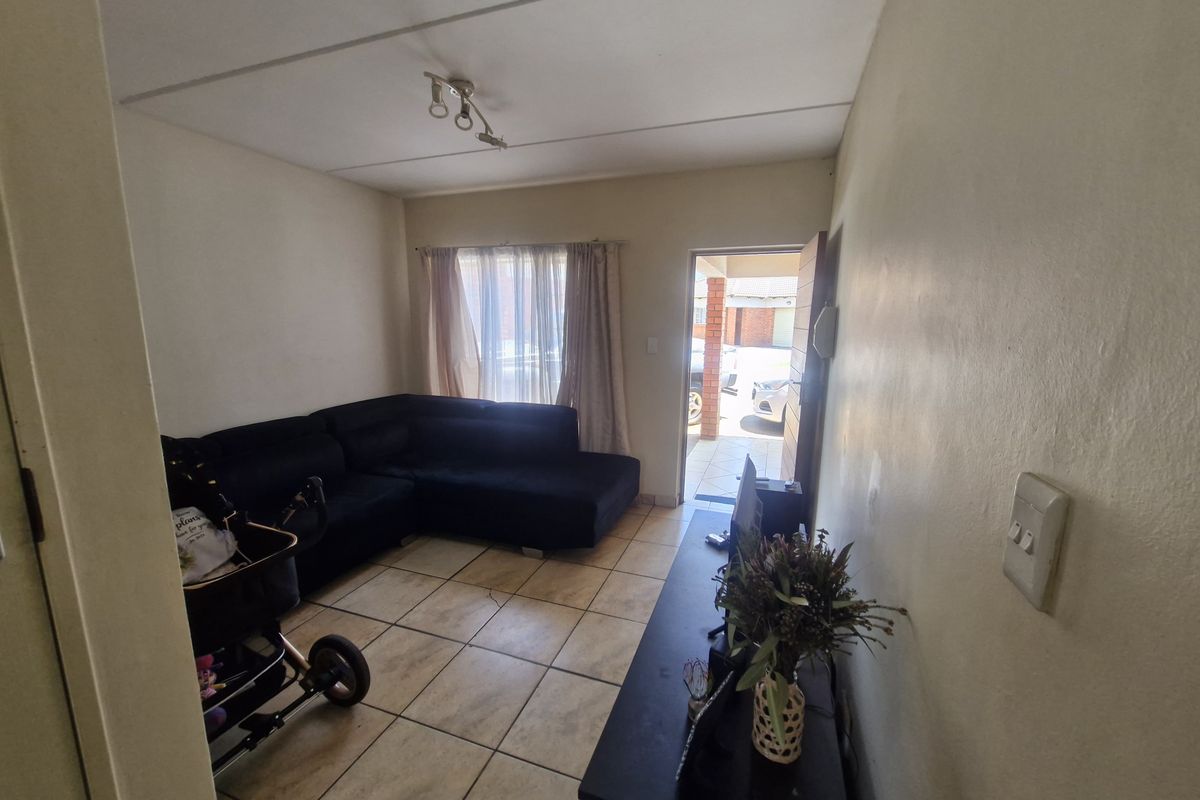 A compact living room featuring tiled flooring and direct access to the exterior, providing a functional space with neutral wall finishes.