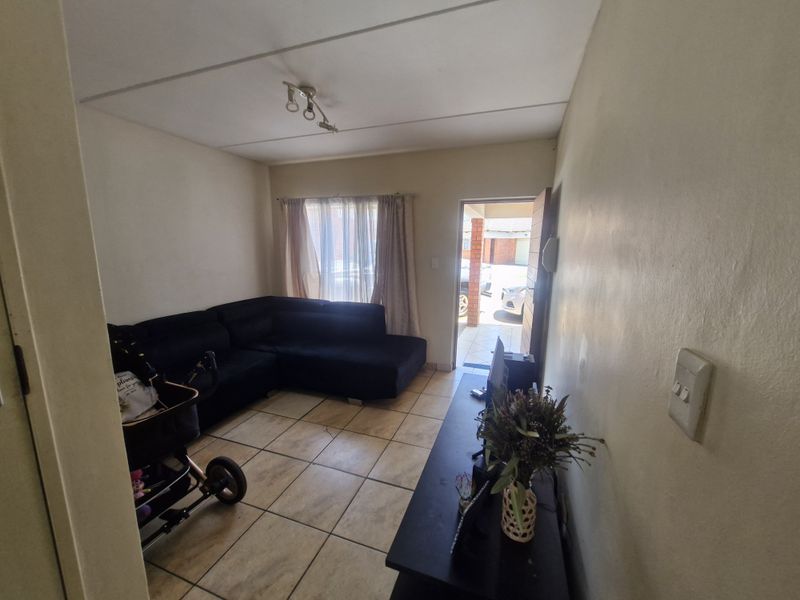 A compact living room featuring tiled flooring and direct access to the exterior, providing a functional space with neutral wall finishes.