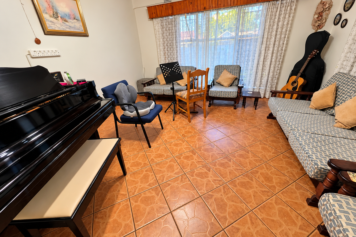 A living room featuring terracotta-style floor tiles and a timber window pelmet, providing a functional space for relaxation or music practice.