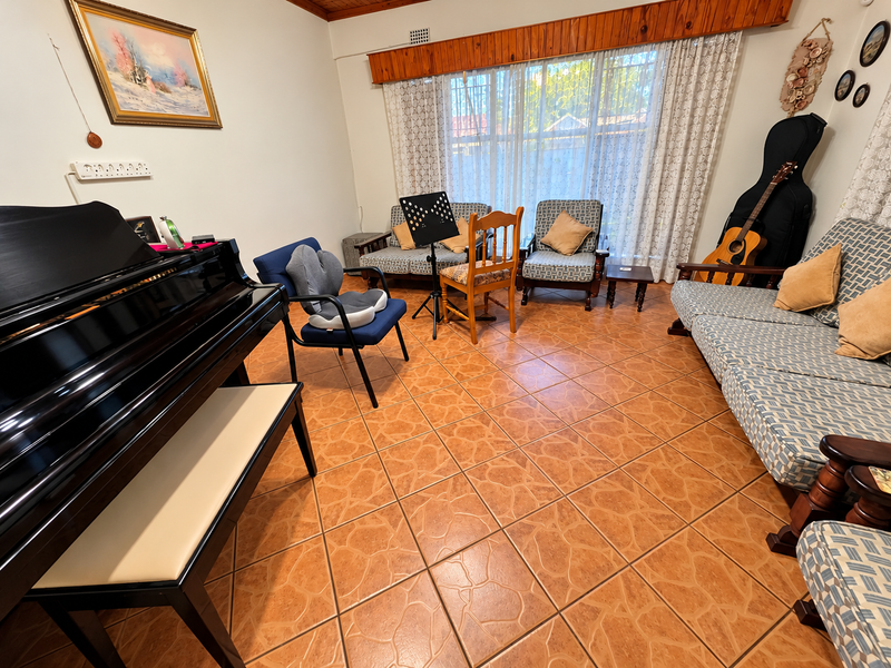 A living room featuring terracotta-style floor tiles and a timber window pelmet, providing a functional space for relaxation or music practice.