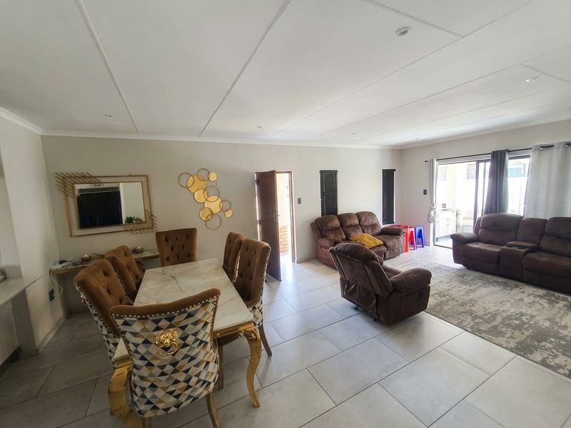 Spacious open-plan living and dining area featuring neutral tiled flooring, recessed lighting, and direct access to an outdoor patio through sliding glass doors.