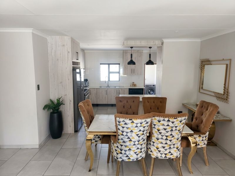 An open-plan dining and kitchen area featuring modern cabinetry, tiled flooring, and pendant lighting, creating a functional and cohesive living space.