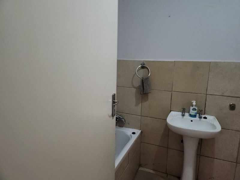 A functional bathroom featuring a pedestal basin and a bathtub with tiled wall finishes.