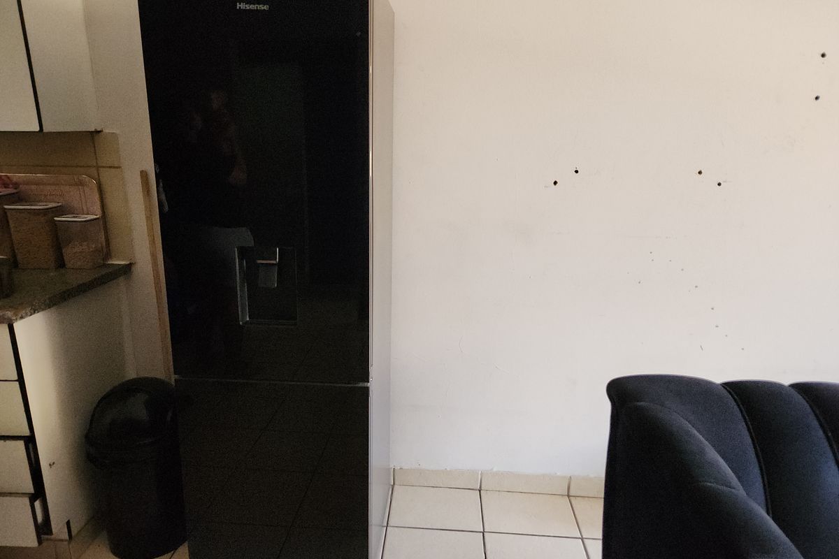 A kitchen area featuring tiled flooring and cabinetry, showing visible wall damage and holes requiring repair.
