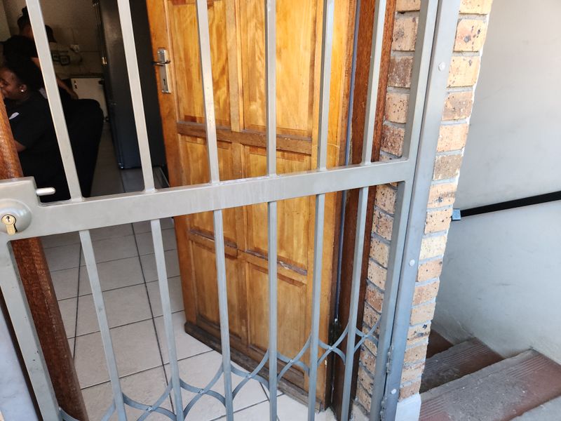 Entrance area featuring a metal security gate, a solid wooden door, and tiled flooring leading into the apartment.