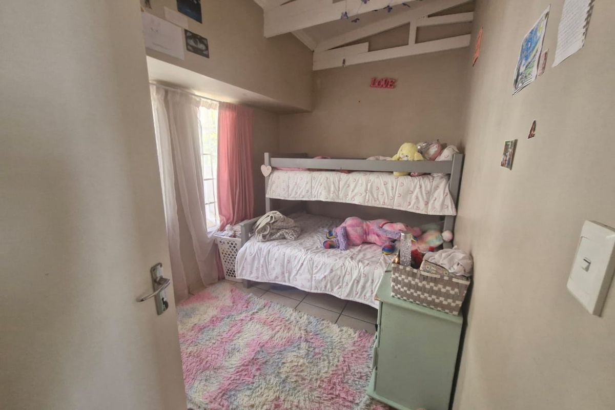 A compact bedroom featuring tiled flooring, exposed ceiling beams, and a window with natural light.