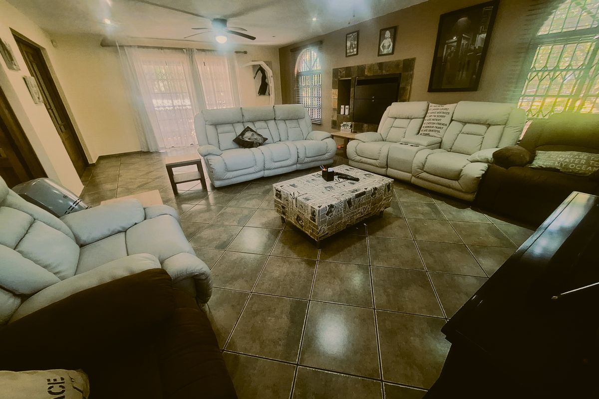 Spacious living room featuring tiled flooring, a built-in fireplace, ceiling fan, and access to the outdoors through sliding glass doors.