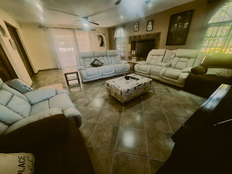 Spacious living room featuring tiled flooring, a built-in fireplace, ceiling fan, and access to the outdoors through sliding glass doors.