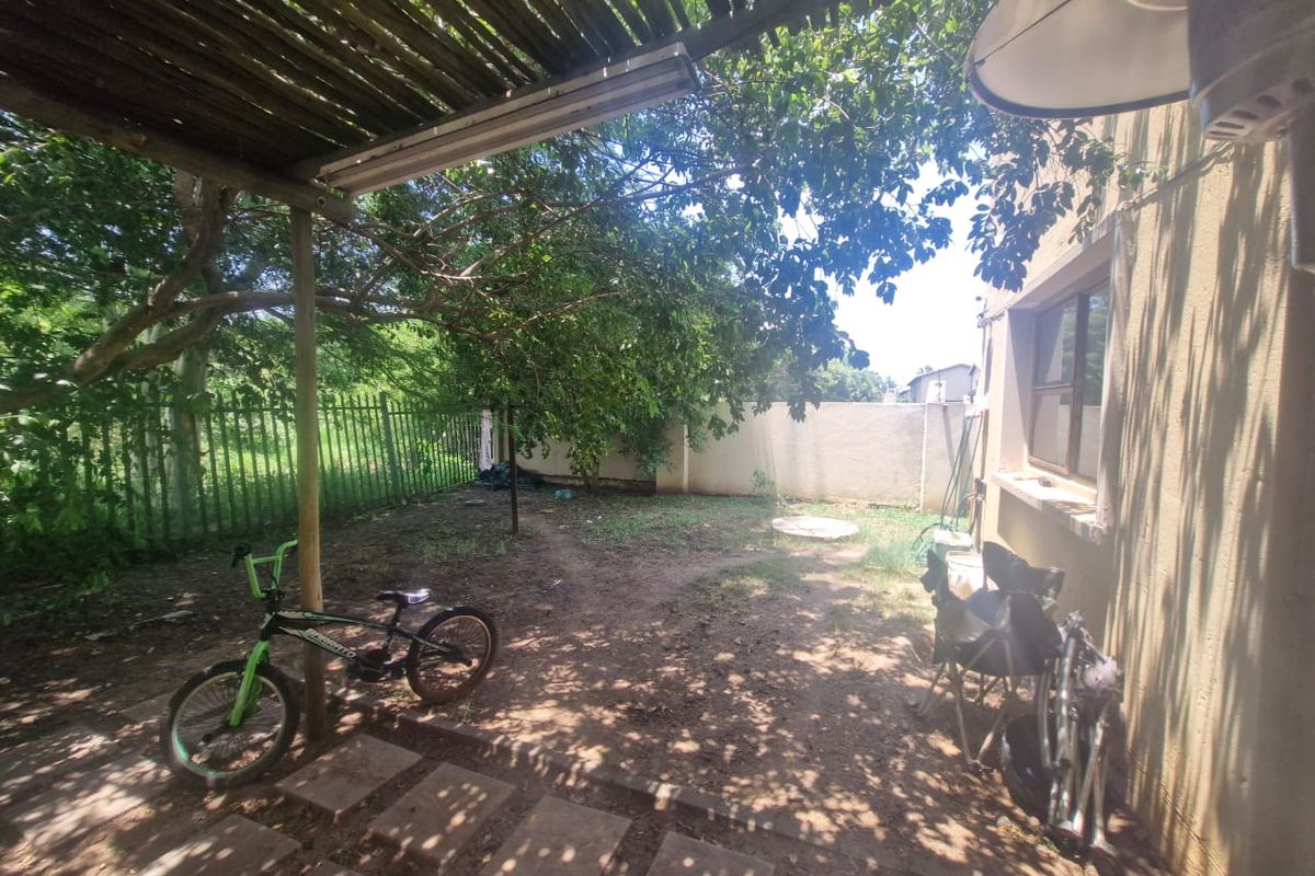 A private rear garden area featuring a covered patio space, perimeter fencing, and established trees, offering potential for landscaping and outdoor improvement.