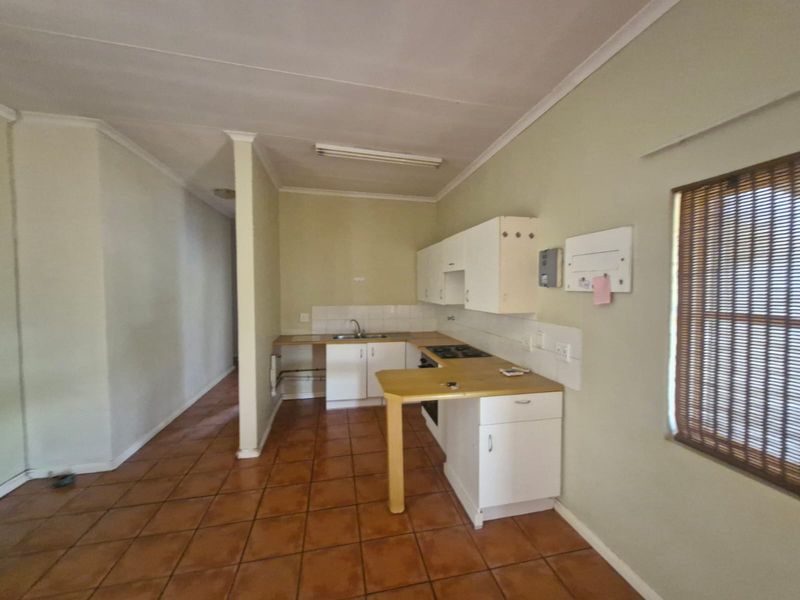 A functional kitchen featuring built-in cabinetry, laminate countertops, a gas hob, and tiled flooring, offering a blank canvas for modern renovation.